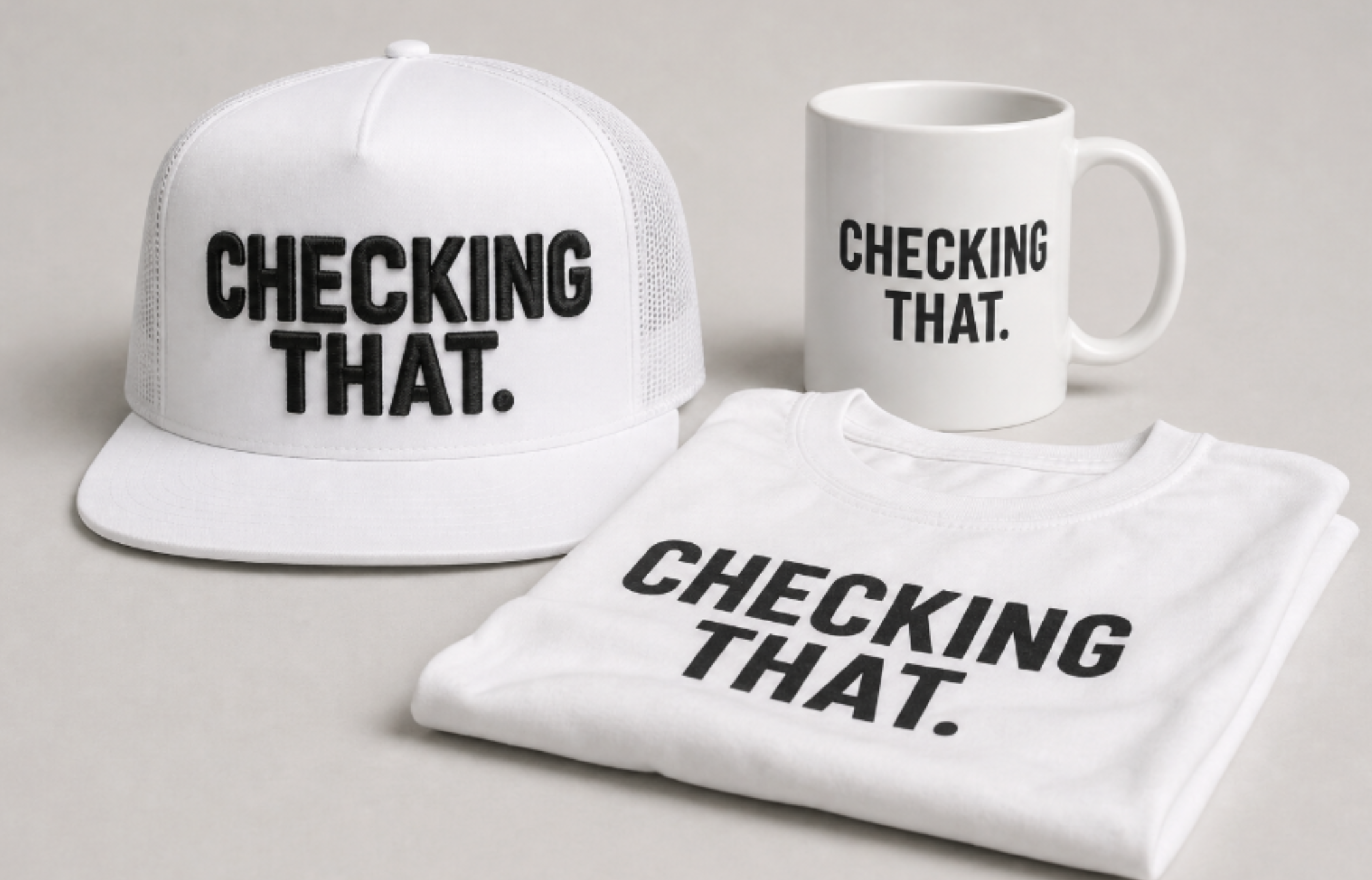 Premium white Checking That trucker hat, folded T-shirt, and mug arranged as an editorial collection